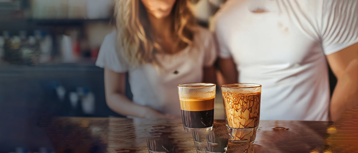 Coffee spilled on a white T-shirt beside two glasses, showing an everyday stain Steradol is designed to tackle