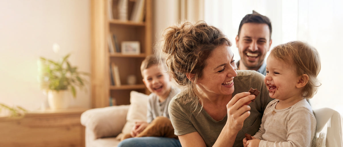 Family sharing chocolate at home, with chocolate stains around a young child's mouth.
